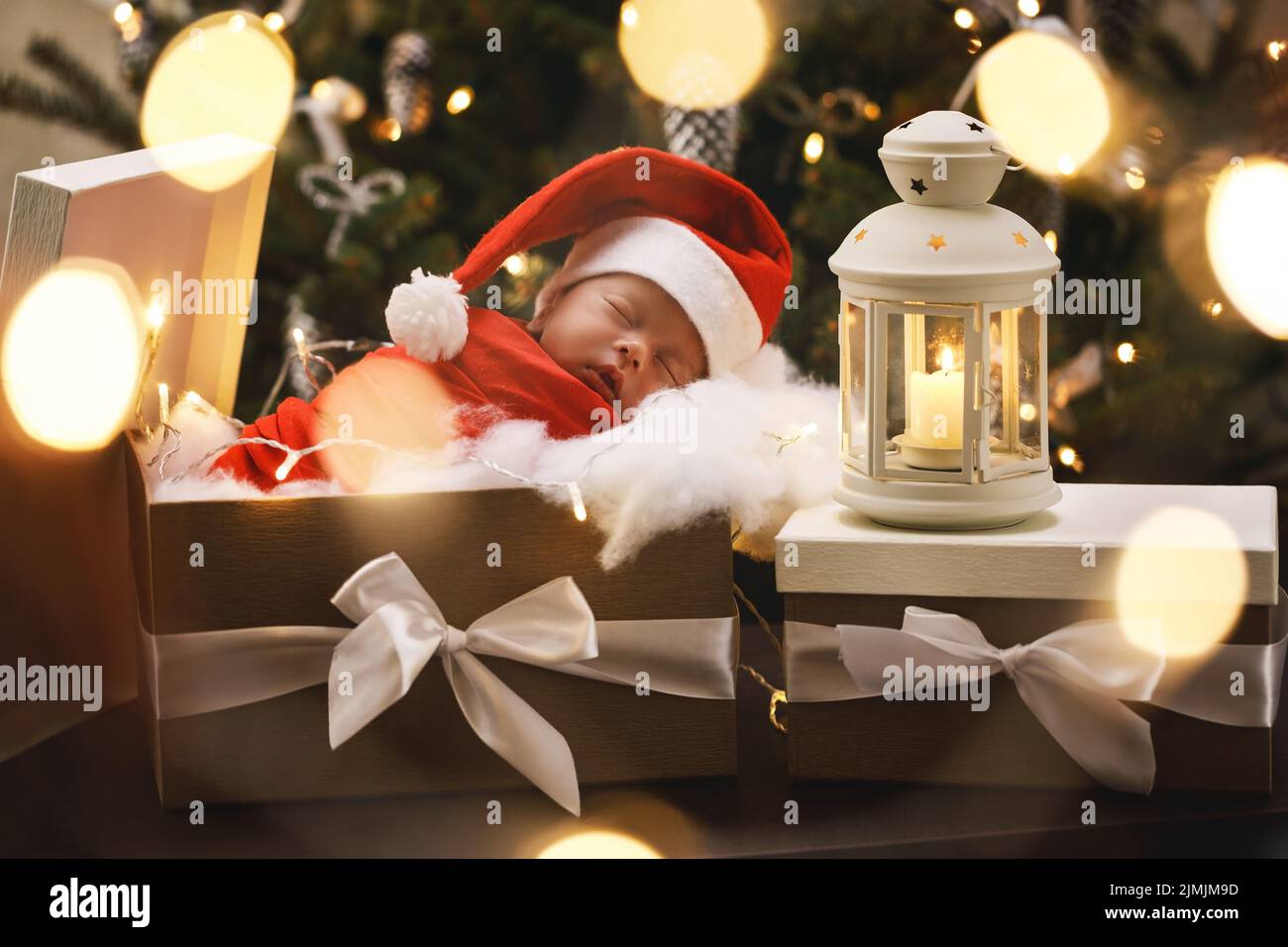 Cute newborn baby wearing Santa Claus hat is sleeping in the Christmas gift box Stock Photo