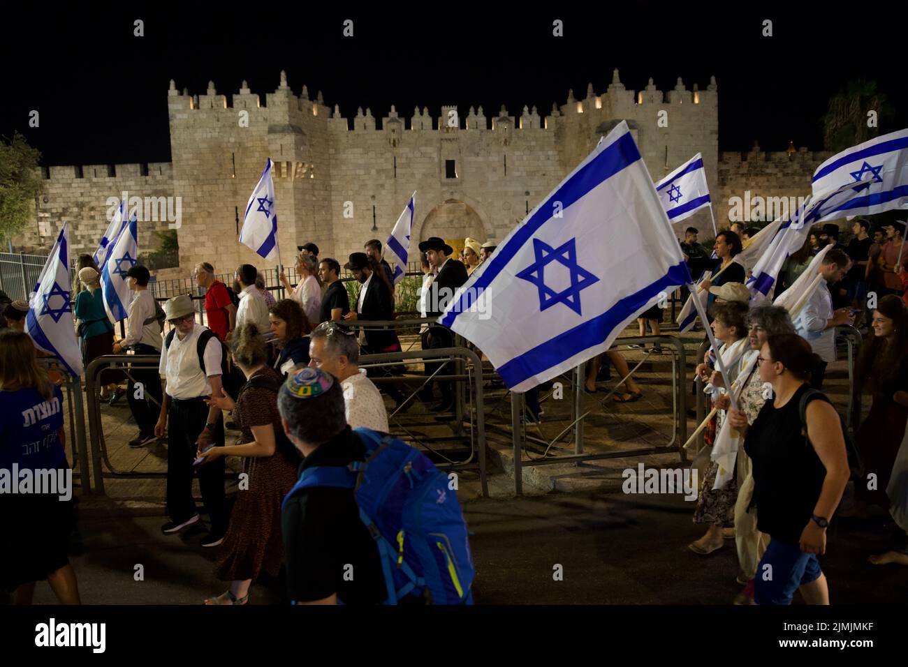 Israeli activists march holding the Israeli flag near Damascus gate in Jerusalem in a traditional procession around the Old City walls marking Tisha B'Av an annual fast day in Judaism, on which a number of disasters in Jewish history occurred, primarily the destruction of both Solomon's Temple by the Neo-Babylonian Empire and the Second Temple by the Roman Empire in Jerusalem. The march was organized by organization promoting the reconstruction of a third Jewish temple on the temple mount. In Jerusalem, Israel on August 6, 2022. (Photo by Matan Golan/Sipa USA) Stock Photo