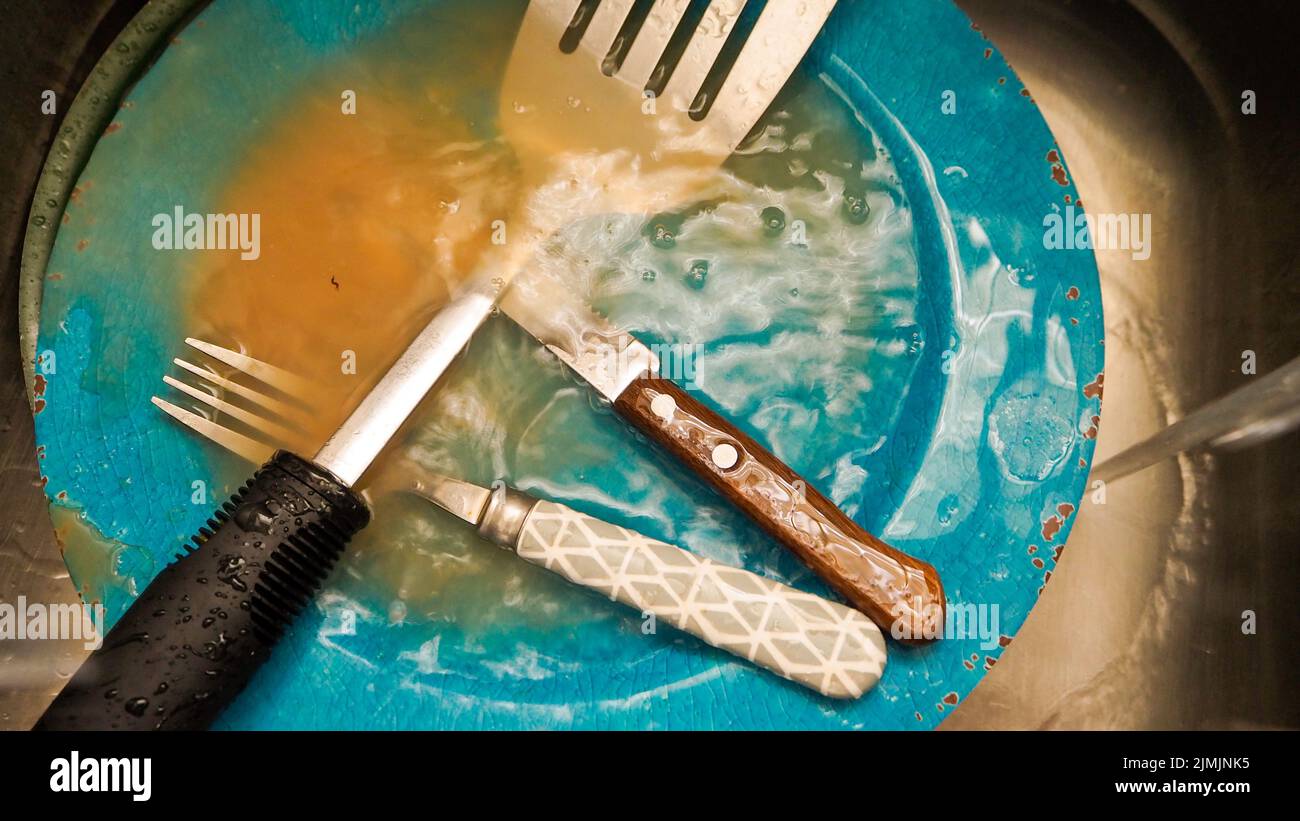 A dirty fork and spoon on a blue plate in a dishwasher Stock Photo Alamy