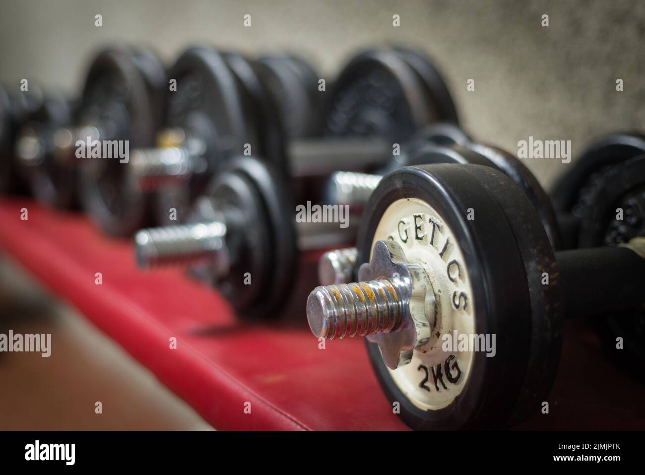 Black desk of free space for your decoration and blurred gym interior.Metal dumbbells and fit life Stock Photo
