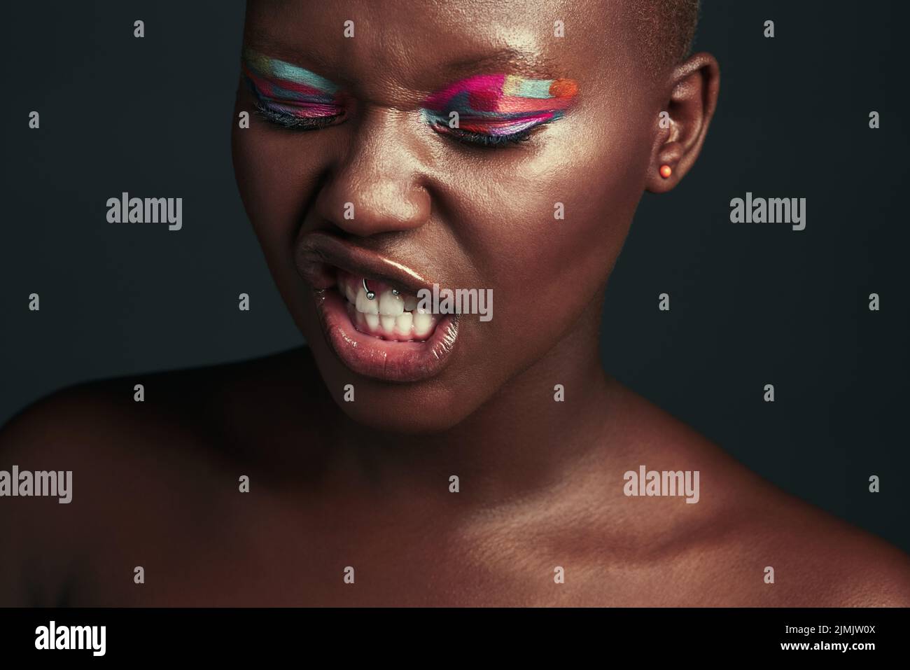 Be a badass and wear that daring eyeshadow. a beautiful woman wearing colorful eyeshadow while posing against a grey background. Stock Photo