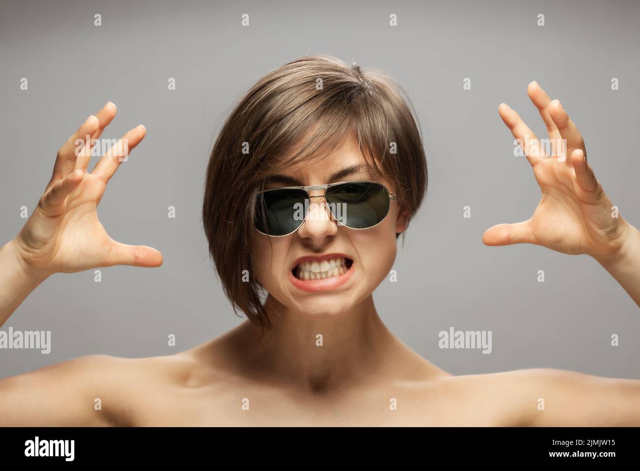 Beautiful girl fashion portrait wearing sunglasses. Surprised angry screaming face expression with hands gesture. Stock Photo