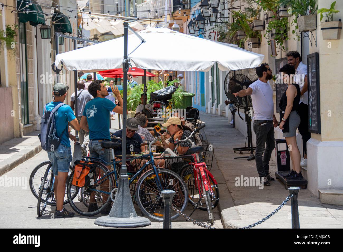 A mixed group of locals and tourists eat and mingle at an outdoor cafe, Havana, Cuba, Stock Photo