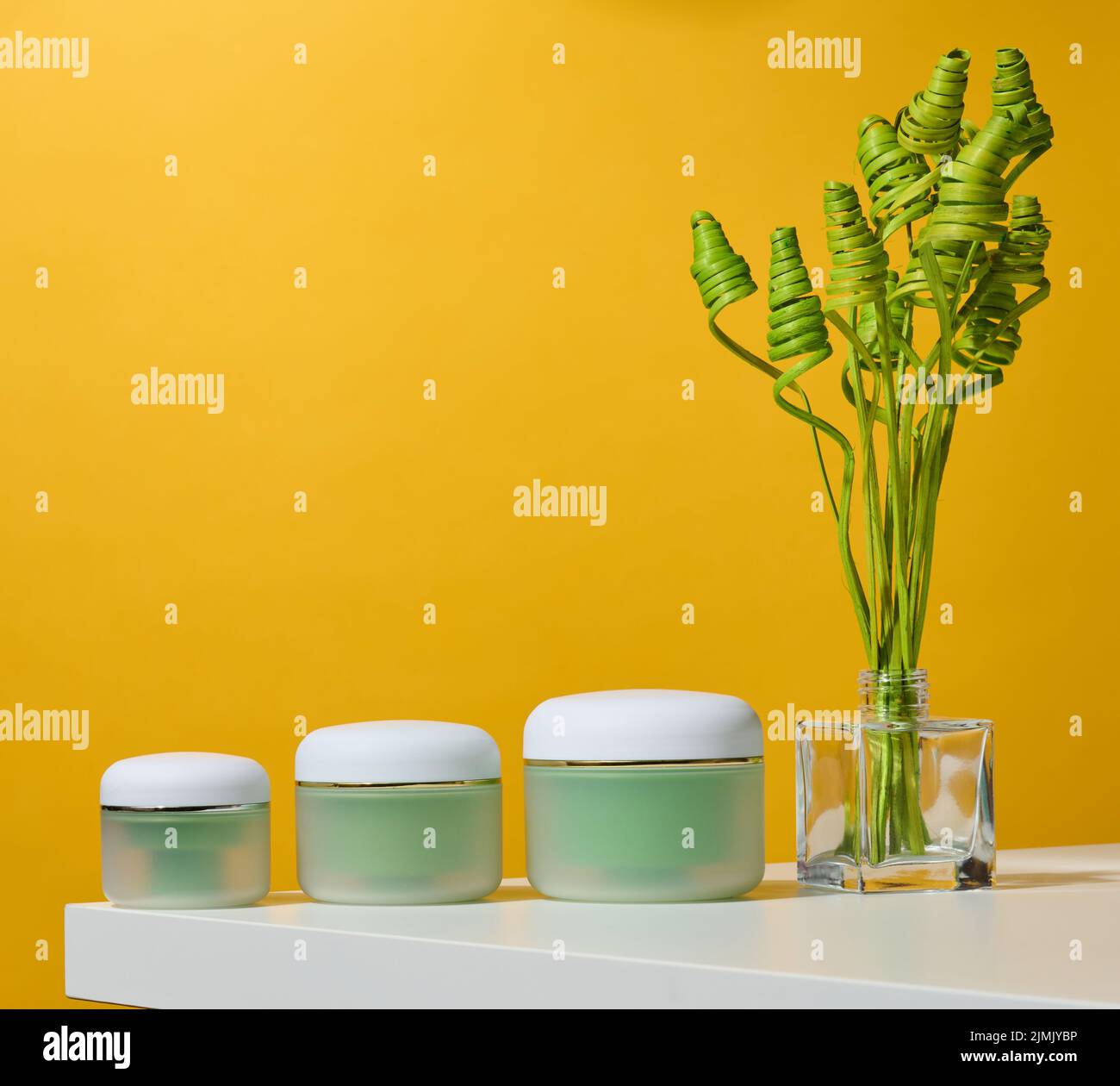 Green jar for cosmetics on a white table. Packaging for cream, gel, serum, advertising and product promotion Stock Photo
