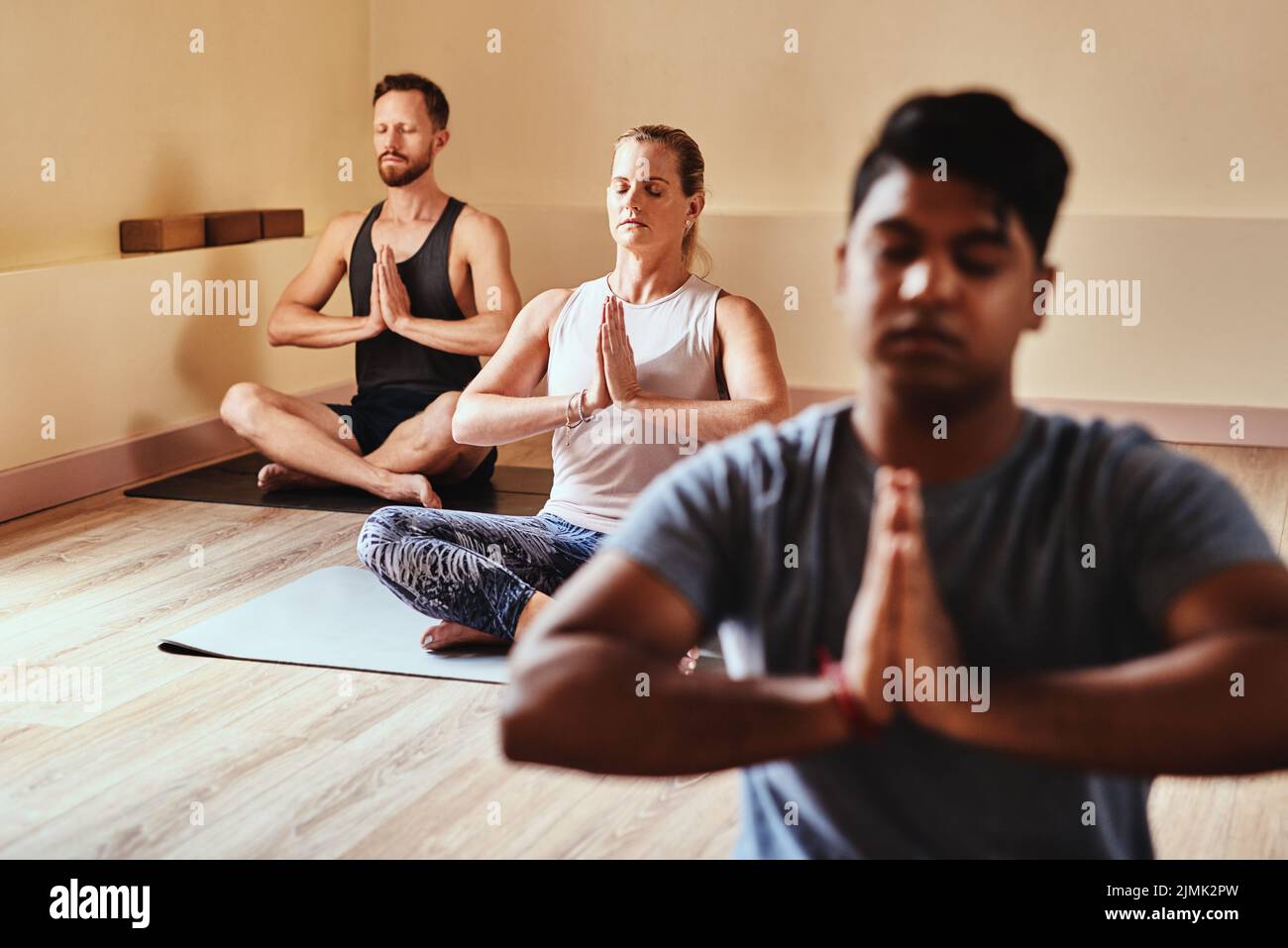 Nothing more needed. a group of young men and women meditating in a yoga class. Stock Photo