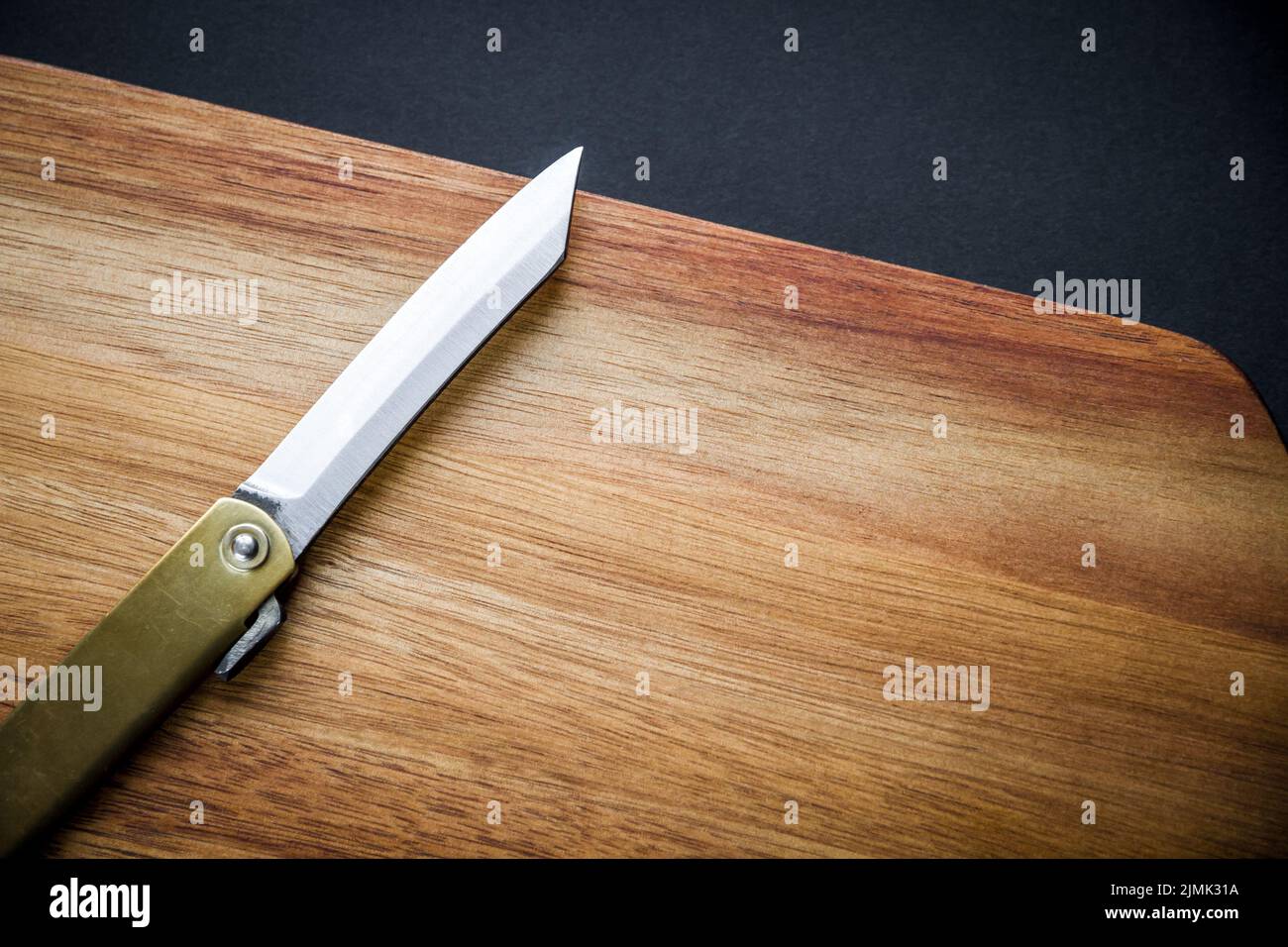 Traditional japanese pocket knife on a wooden cutting board Stock Photo