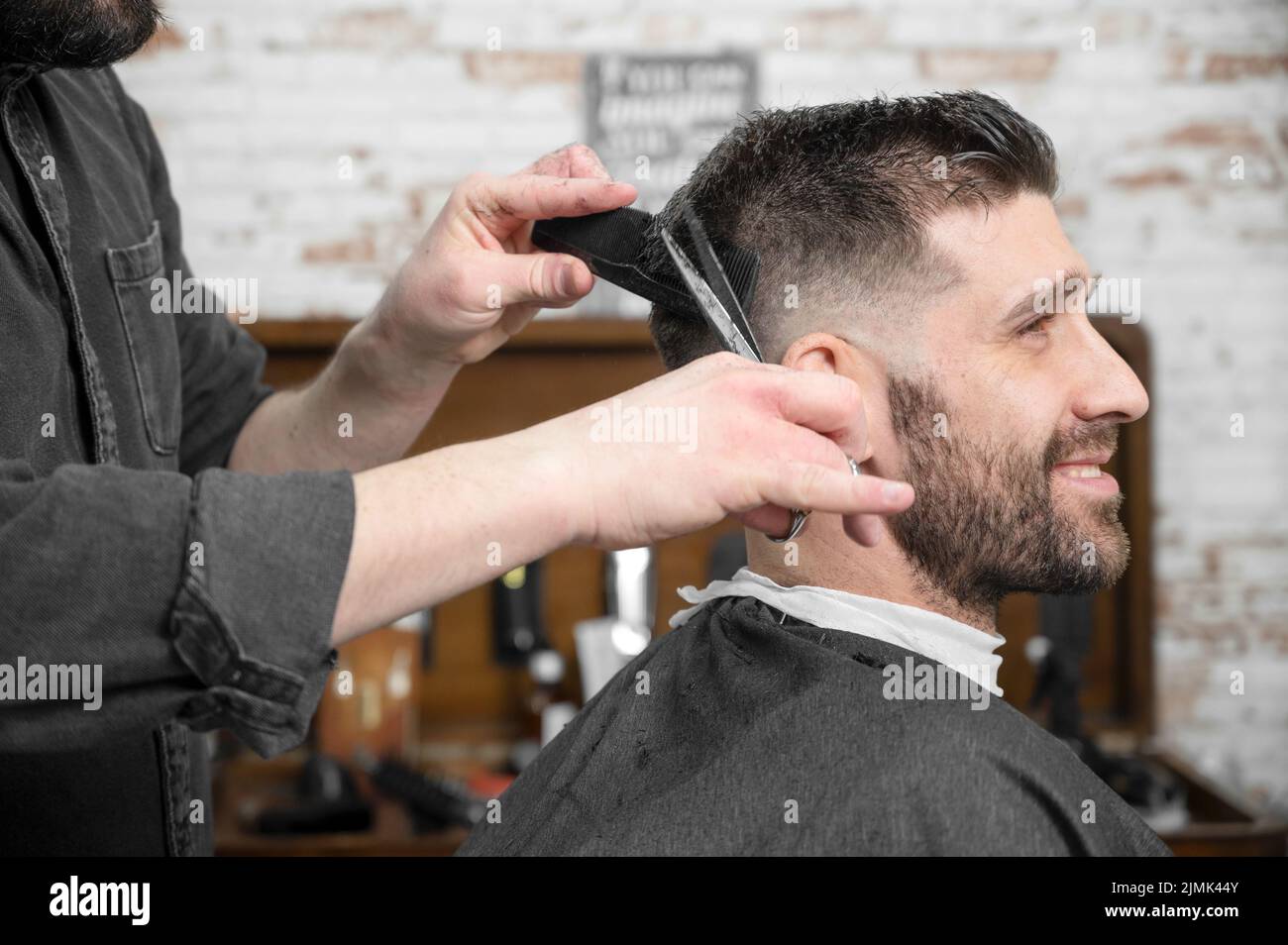 Barber cutting hair with scissors to a handsome young man Stock Photo Alamy
