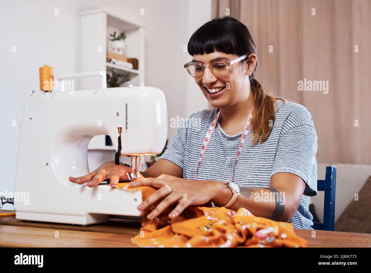 I have my own style therefore I design my own clothes. a young woman stitching fabric using a sewing machine at home. Stock Photo