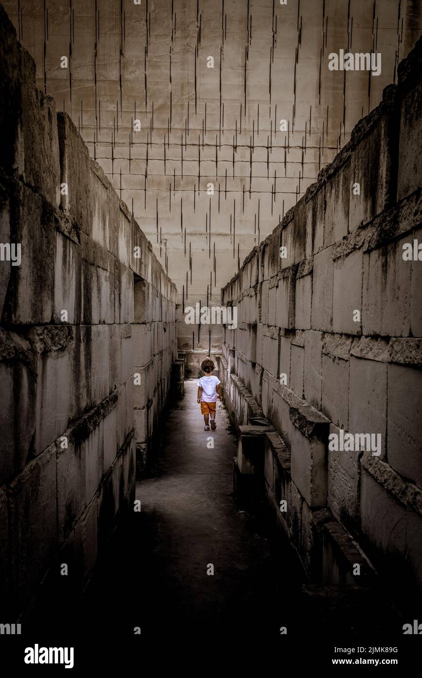 Caucasian young kid walking in a labyrinth. Conceptual image for dangerous situation during childhood. Stock Photo