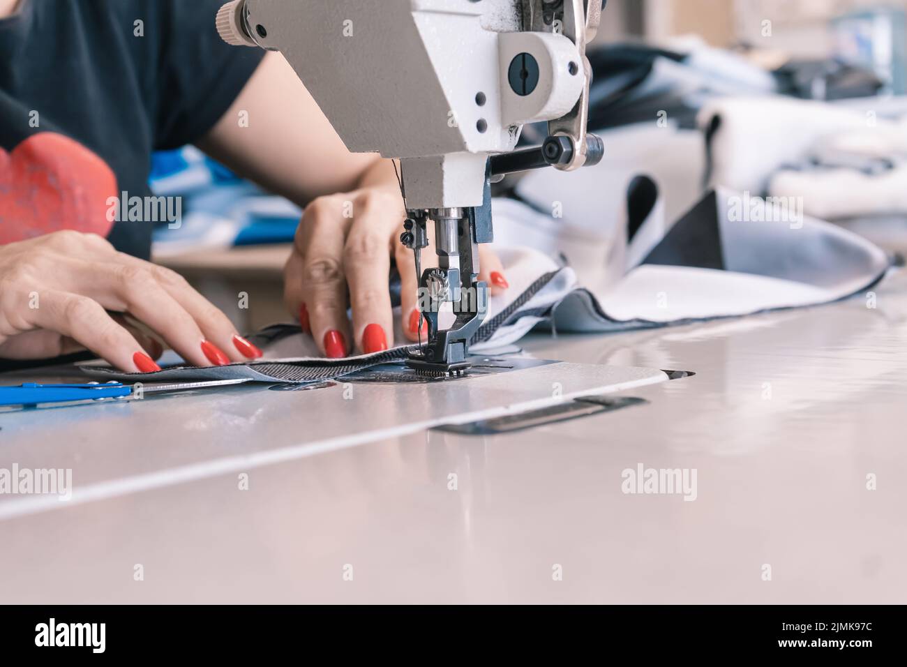 The seamstress sews at the sewing machine, threads the fabric. Women's