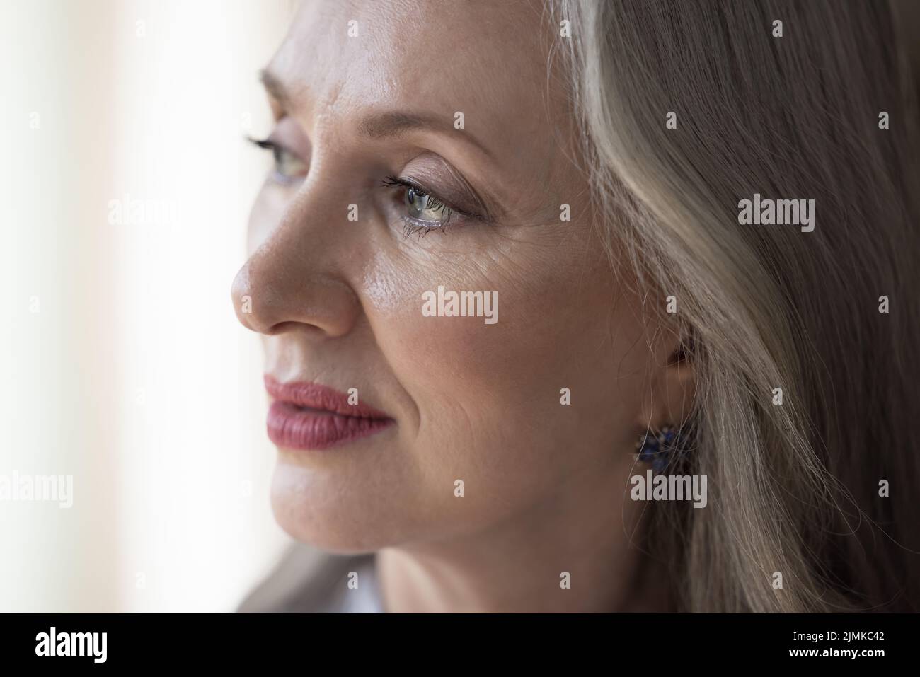 Thoughtful senior grey haired woman looking away in deep thought Stock Photo