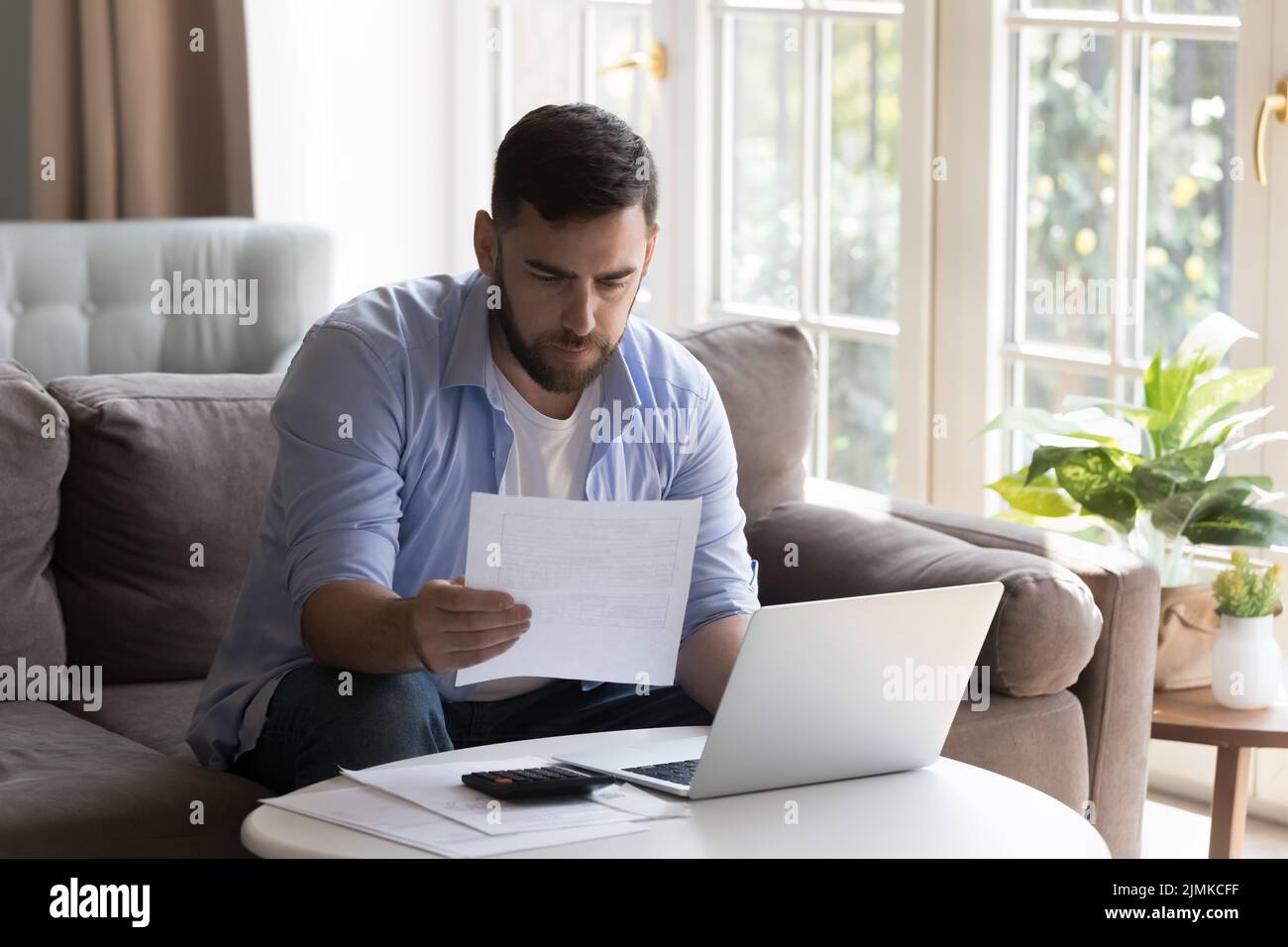 Man reading documents, examining bills doing paperwork at home Stock Photo