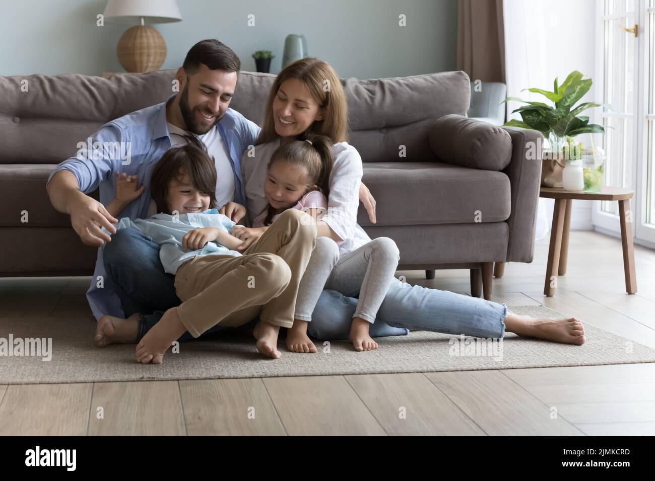 Parents tickling little kids seated on floor at home Stock Photo Alamy