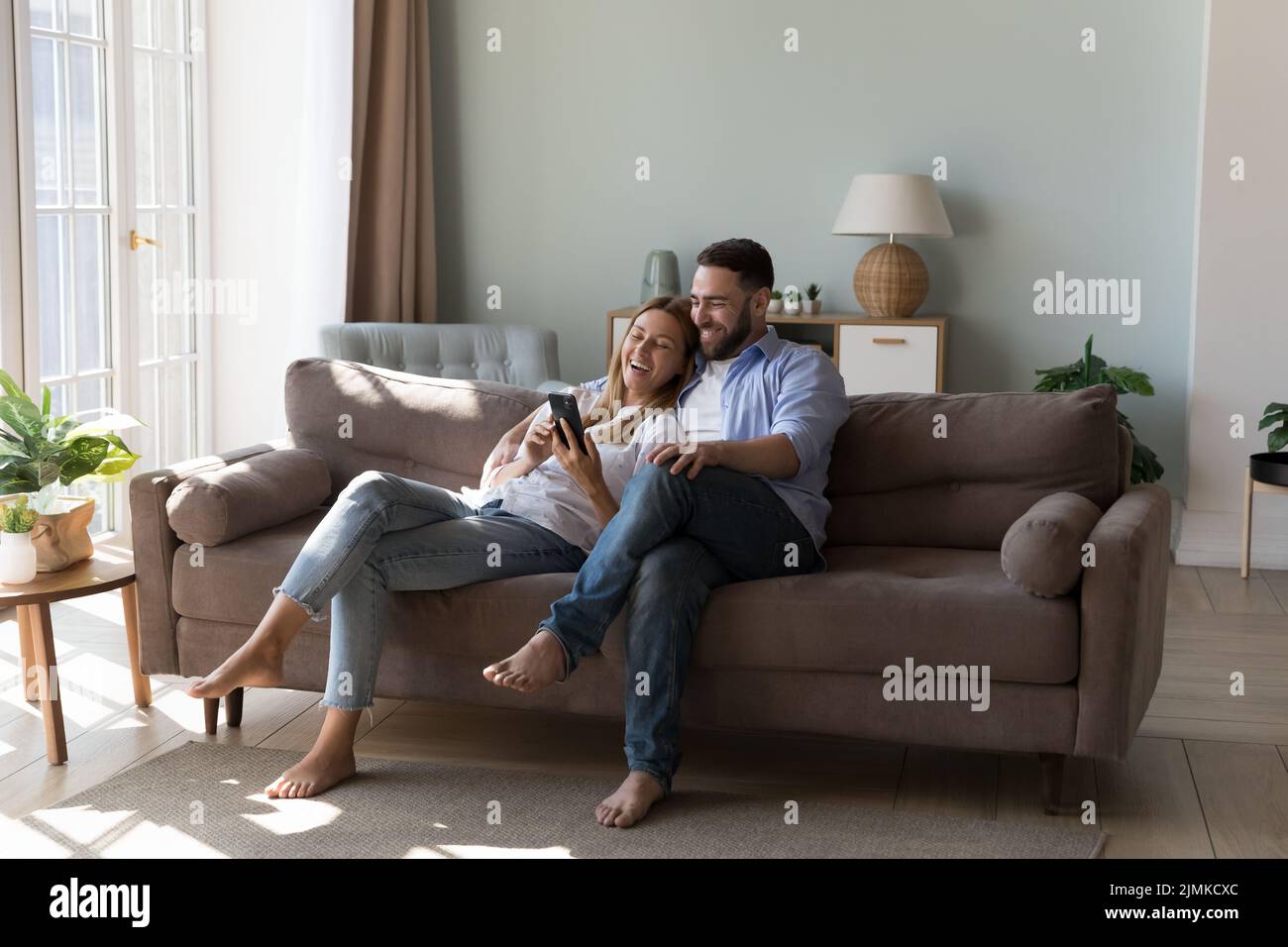 Couple relaxing on sofa spend time on internet using smartphone Stock Photo