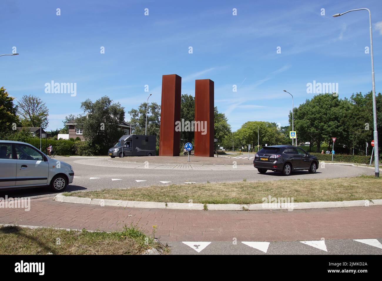 Two towers on a roundabout as the entrance to the village of Bergen in summer. Made (2002) from rust-coloured Cor-ten steel. Netherlands, August. Stock Photo