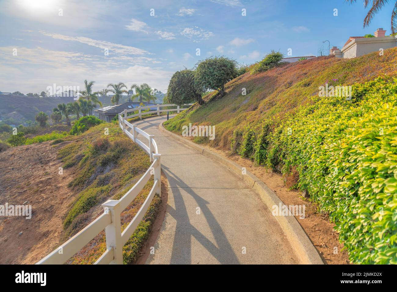 Concrete trail in the middle of a slope with white fence barrier on the