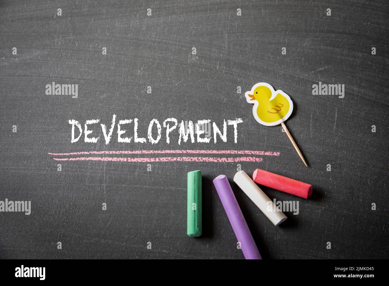 Development. Text and colored pieces of chalk on a dark blackboard. Stock Photo