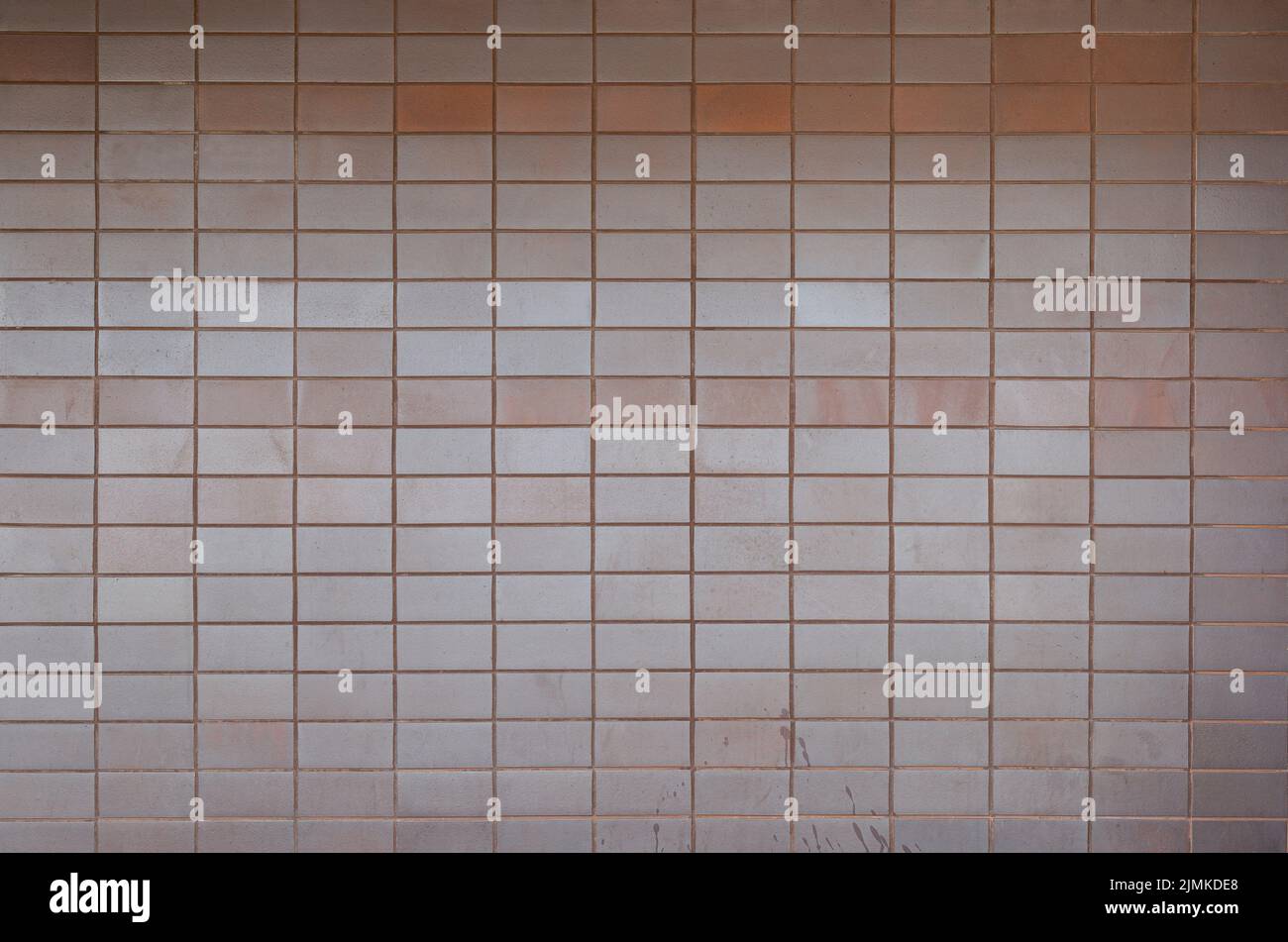 Wall made of tiles or blocks with some stains, front view. High resolution full frame textured background. Copy space. Stock Photo