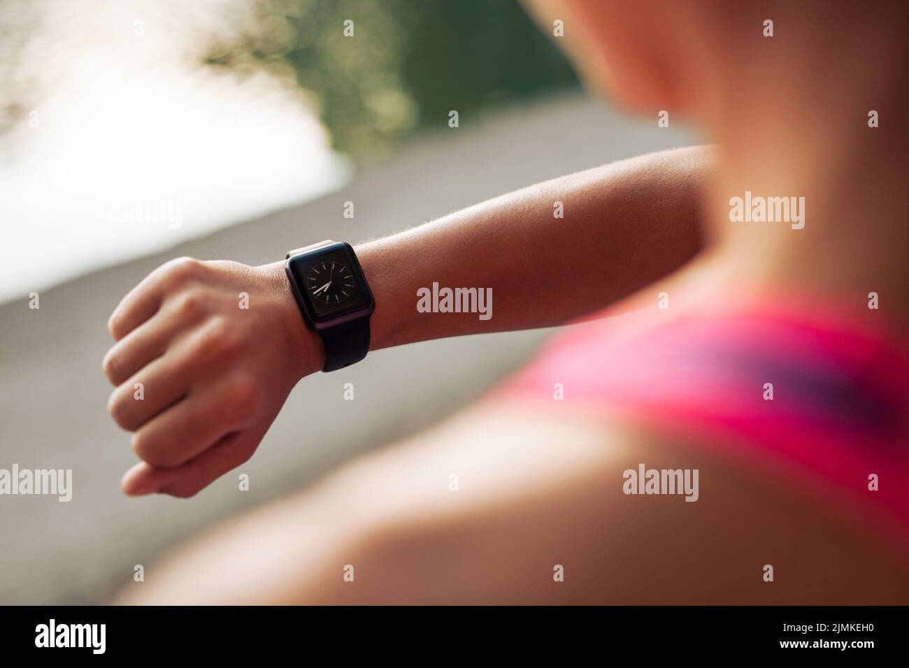 Close up image of young woman checking the time on smartwatch device after jog, outdoors. Stock Photo