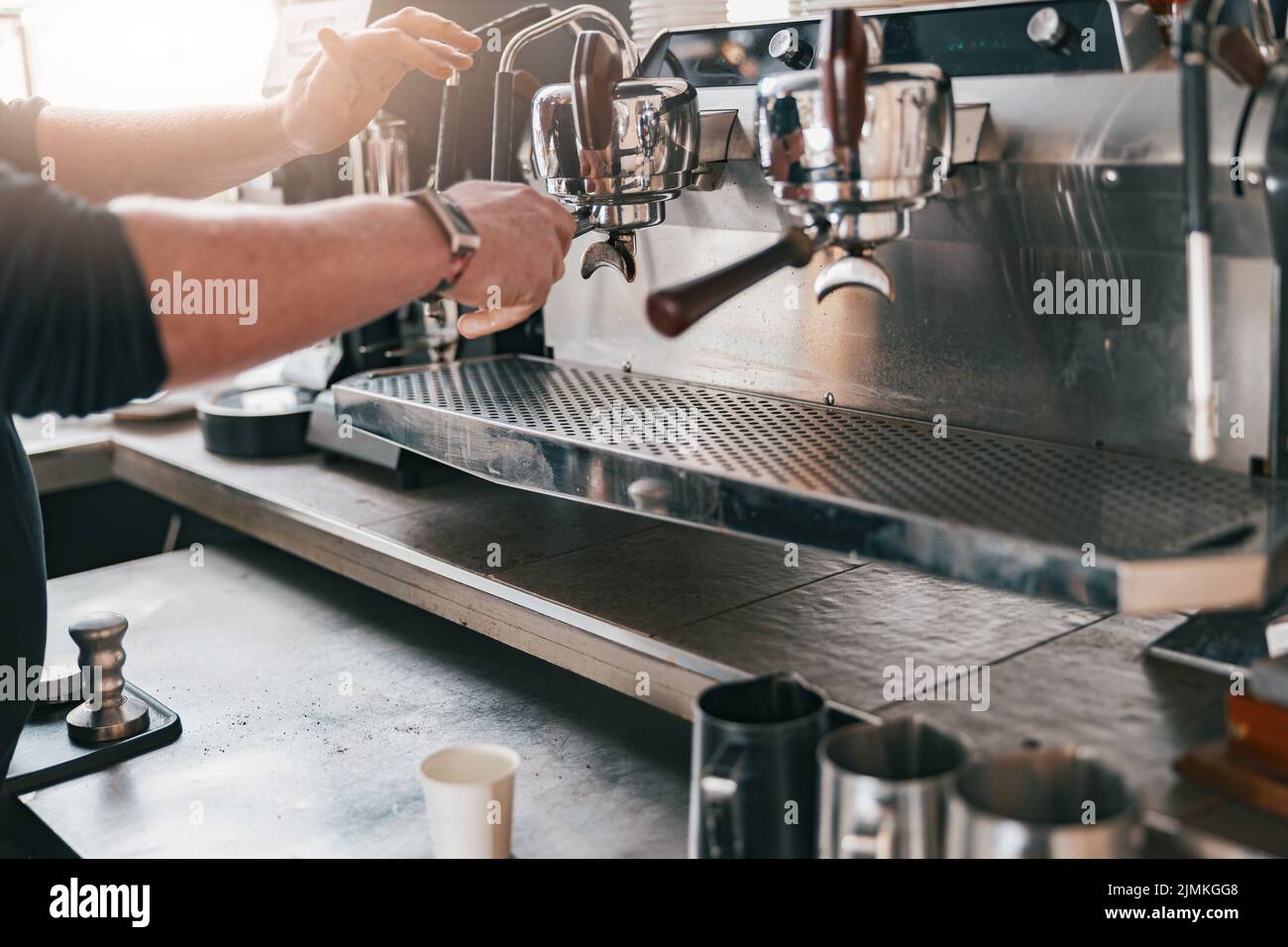 Professional barista warming milk In metal jug with steam of coffee