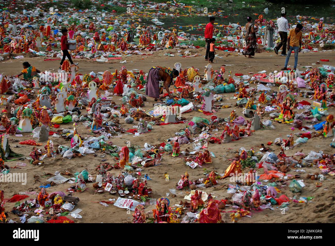 A woman collects recyclable items from the idols of Hindu goddess Dashama, left by devotees on the banks of the river Sabarmati a day after the 'Dashama' festival, in Ahmedabad, India, August 7, 2022. REUTERS/Amit Dave     TPX IMAGES OF THE DAY Stock Photo