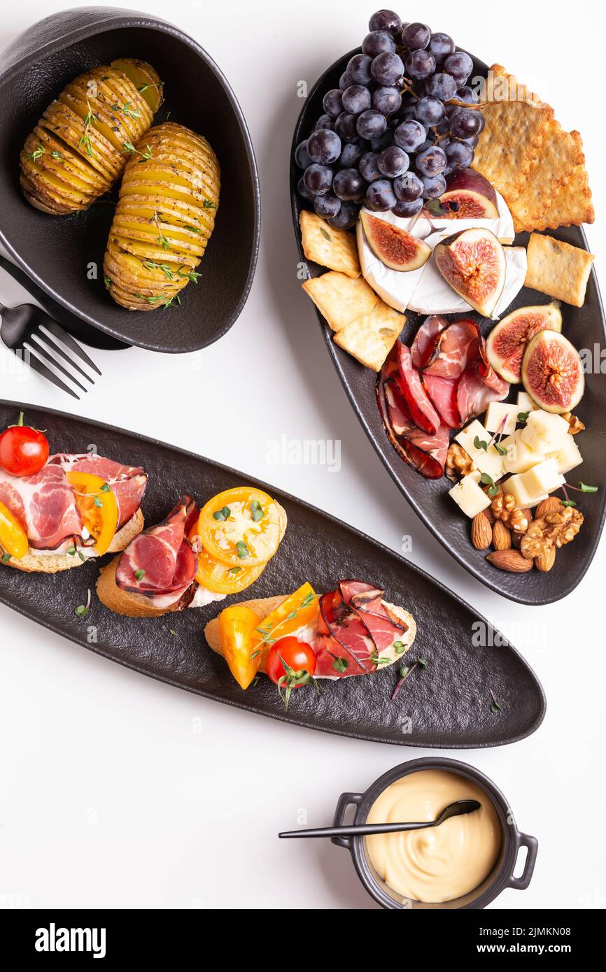 Dinner with grilled potato and assorted cheese, prosciutto and fruits, bruschetta on a plate Stock Photo
