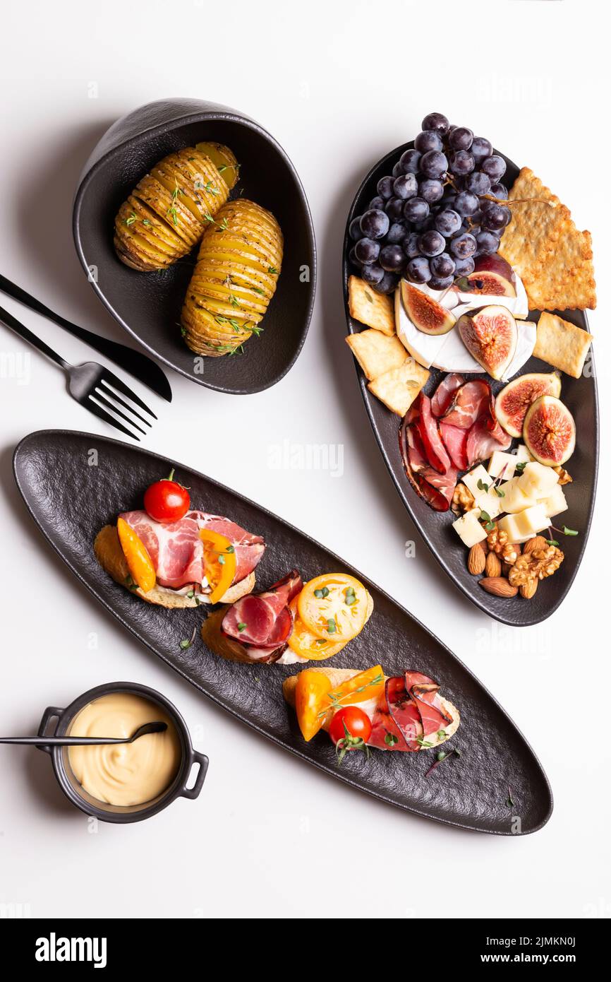 Dinner with grilled potato and assorted cheese, prosciutto and fruits, bruschetta on a plate Stock Photo