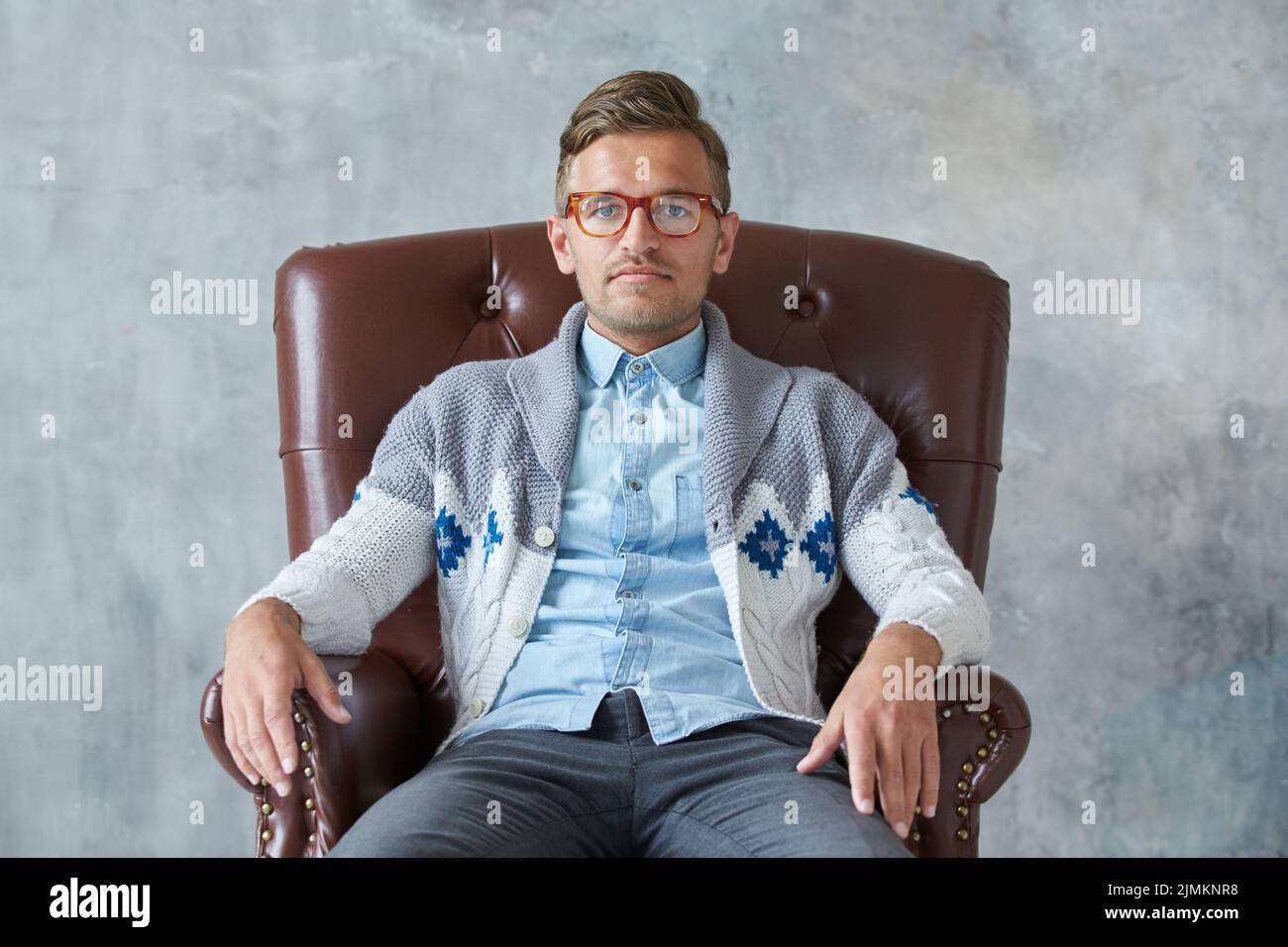 Portrait of a stylish intelligent man with glasses stares into the camera, good view, small unshaven, charismatic, blue shirt, g Stock Photo