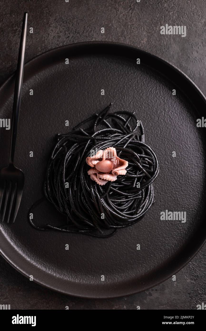 Black spaghetti with cuttlefish ink with boiled octopus Stock Photo - Alamy