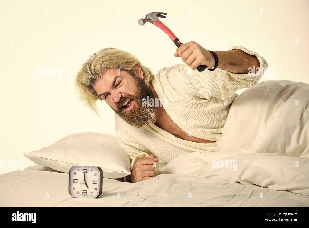 Tired man in the bed not happy. suffering insomnia and sleep disorder. bedtime. Destroy the Clock. handsome angry man lies in bed indoors wake up turn Stock Photo