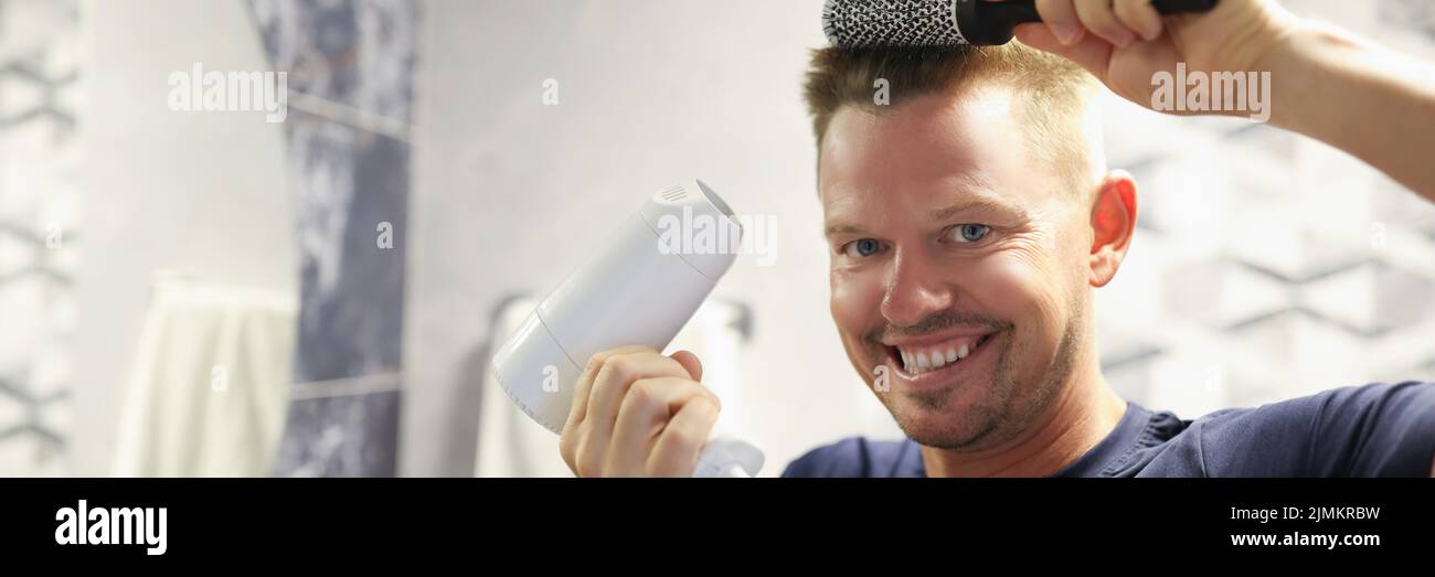 Happy man doing his own blow-drying at home Stock Photo
