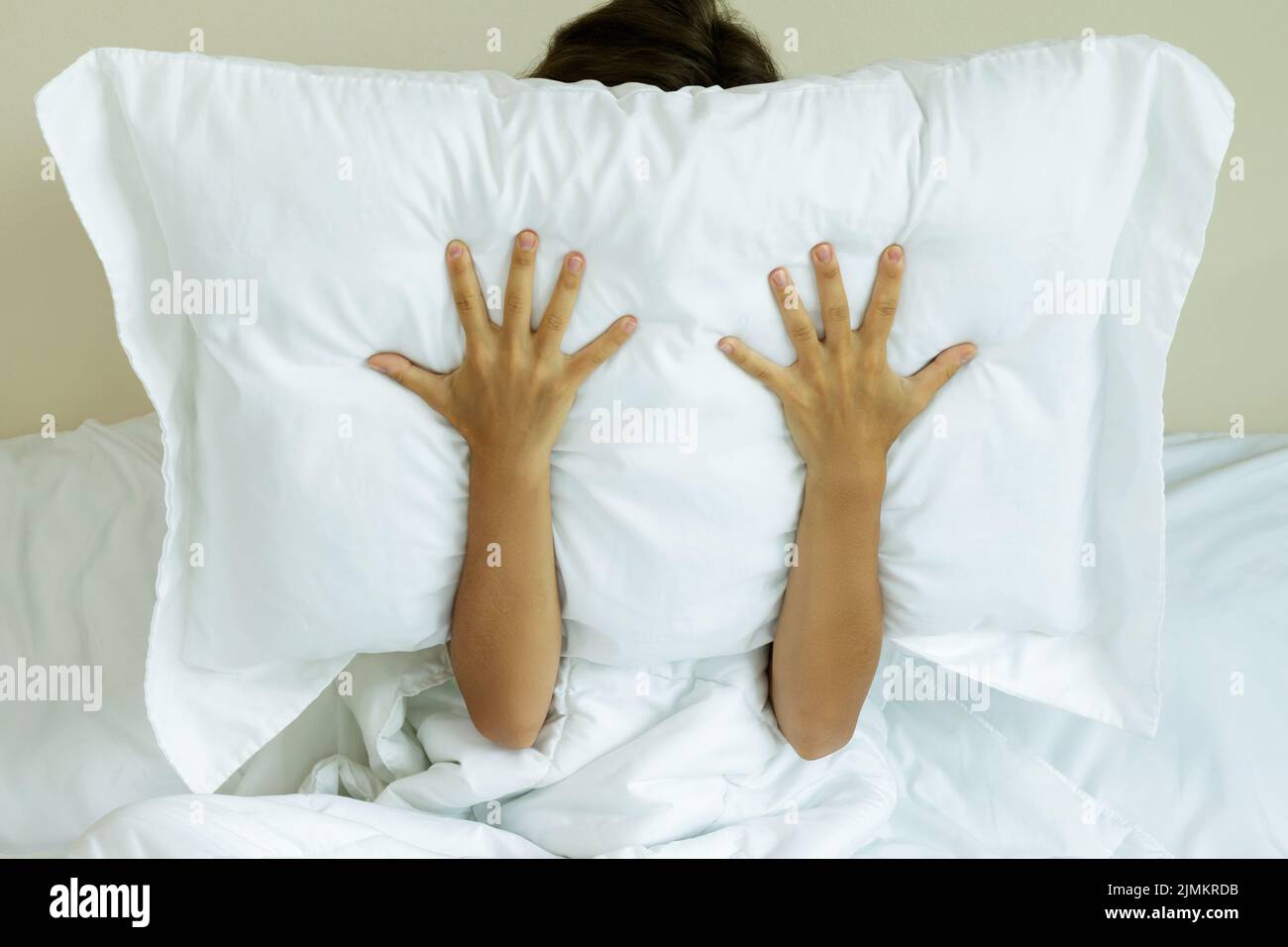 Woman with pillow on her head because she don't wanna hear noise Stock
