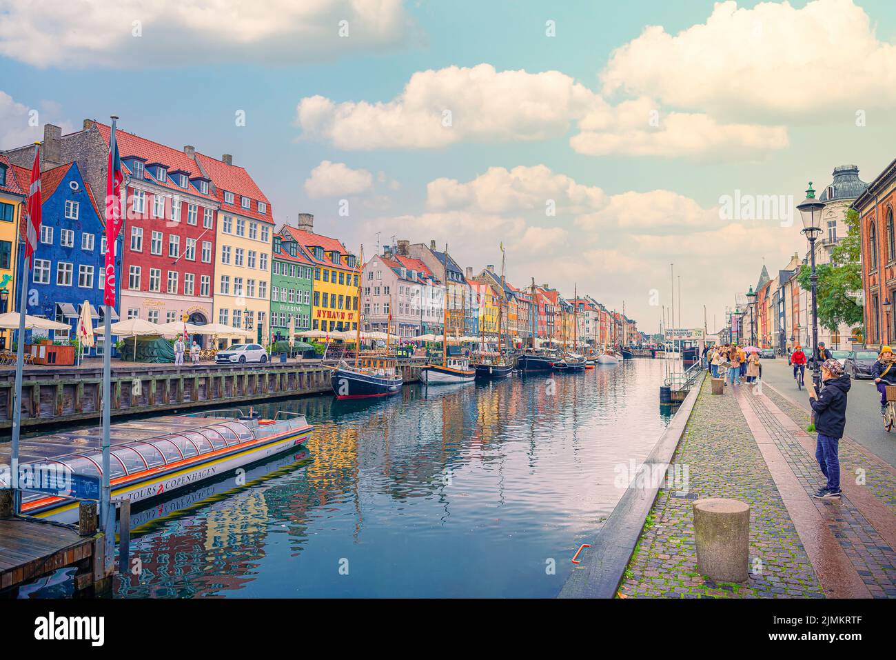 People walk on the Nyhavn street - a popular place for walking with many boats and colorful houses in Copenhagen, Denmark Stock Photo