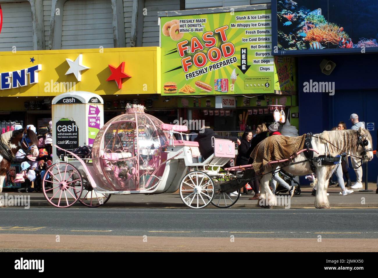 People around a coach and horse on the golden mile in blackpool outside the sealife centre and amusement arcades Stock Photo