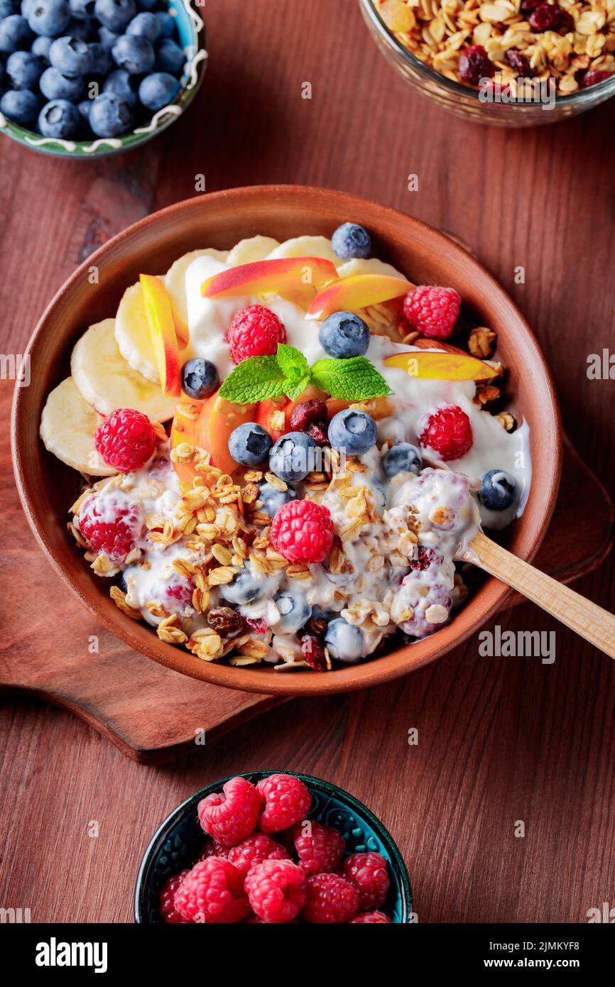 Bowl of homemade granola with yogurt and fresh berries on wooden