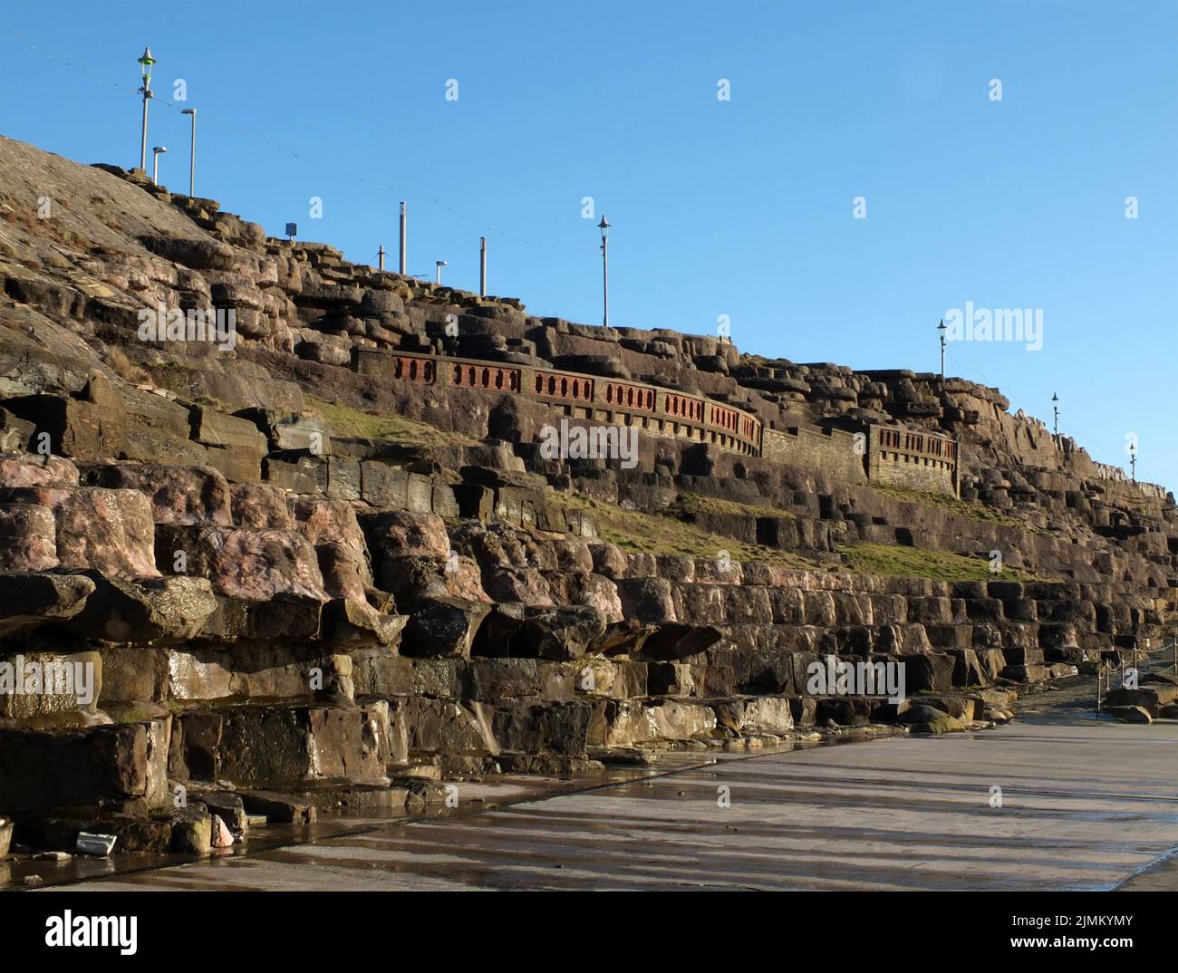 The cliffs area of blackpool with artificially sculpted rocks and walkways along the promenade in afternoon sunlight Stock Photo