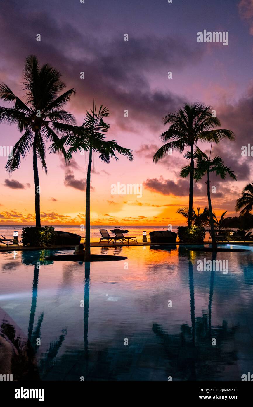 Sunset tropical pool with palm trees, sunset by the pool with palm trees during vacation in Mauritius Stock Photo