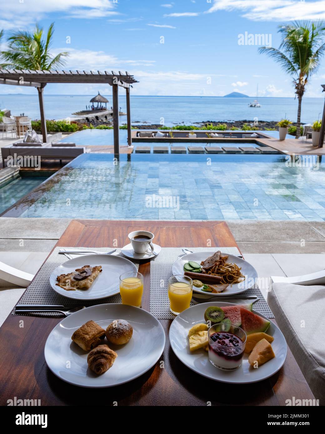 Breakfast at a beach with palm trees and pool in Mauritius, tropical setting with breakfast Stock Photo