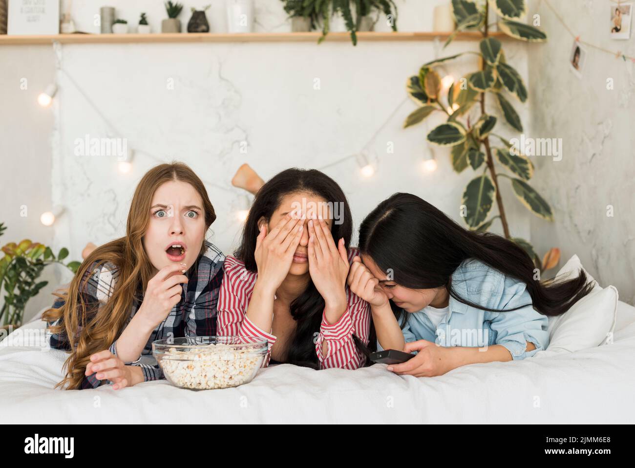 Girls lying bed eating popcorn having fun Stock Photo