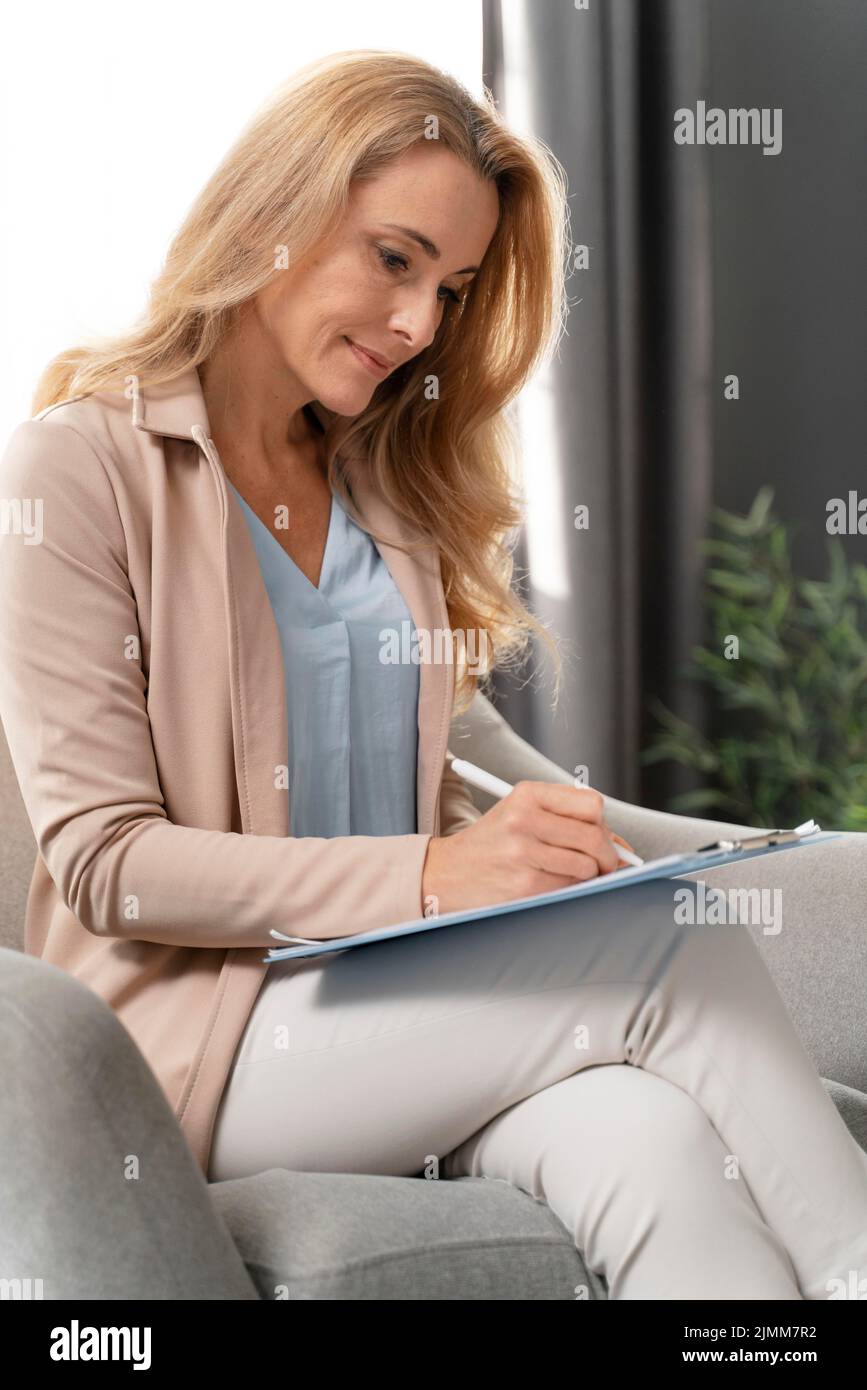 Mid shot woman therapist writing clipboard Stock Photo