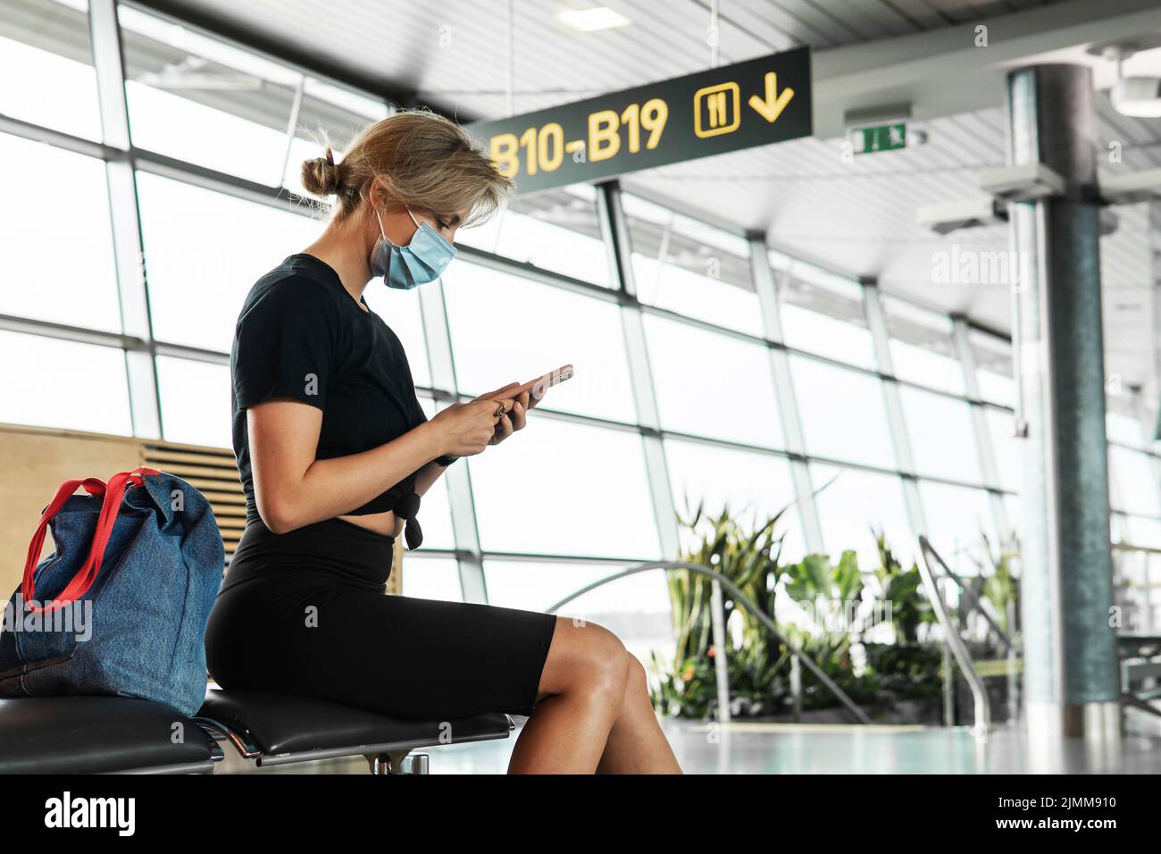 Young woman is a wearing prevention mask in an airport during flight awaiting Stock Photo