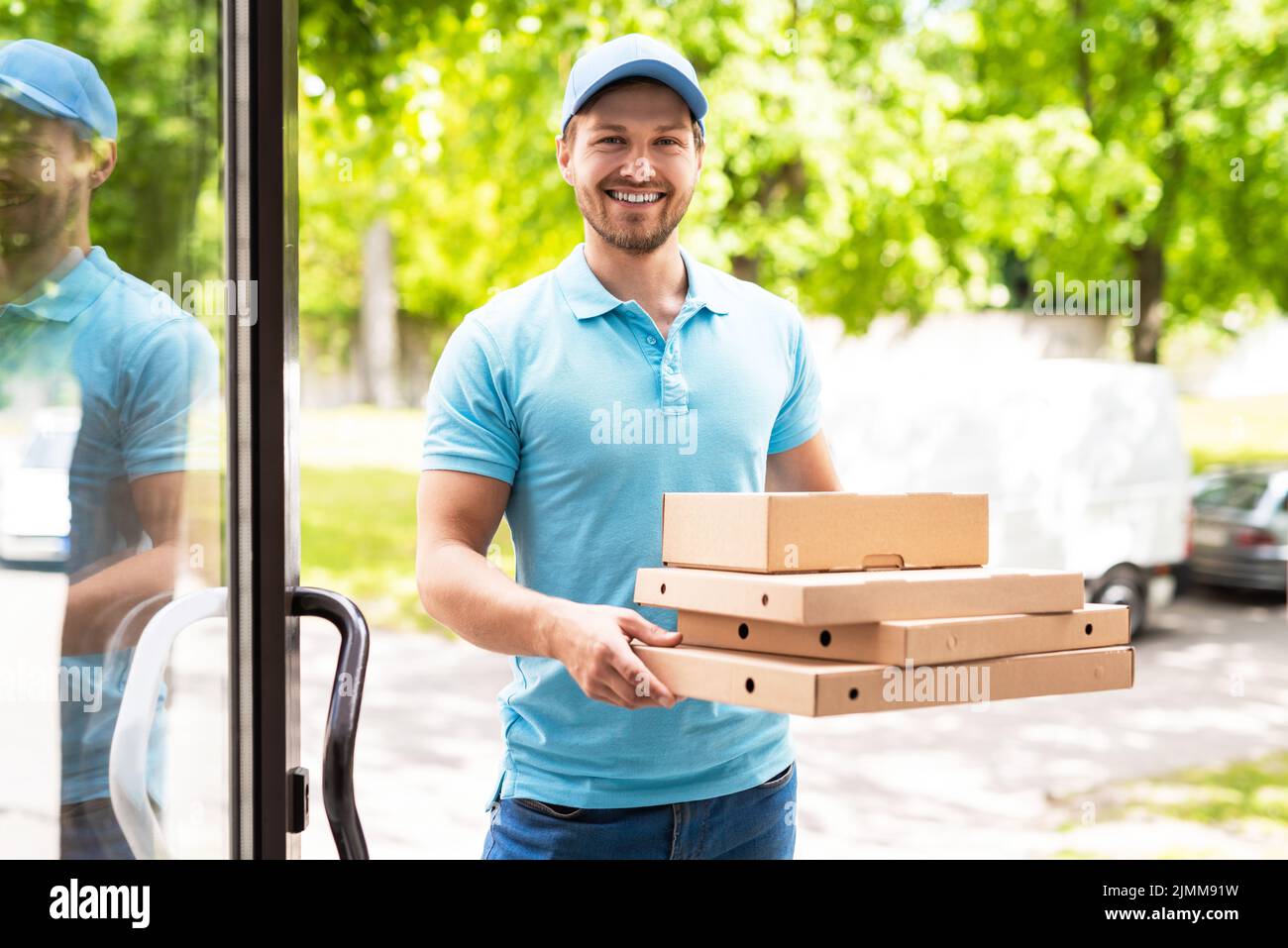 Smiling courier during pizza delivery near an entrance Stock Photo