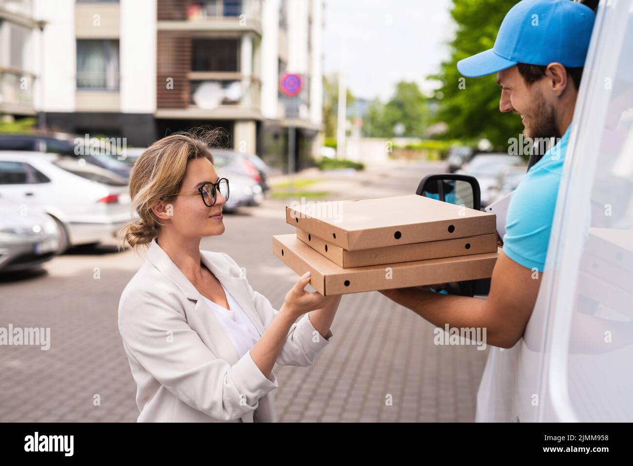 Delivery man in a white van delivers pizza to a woman client Stock ...