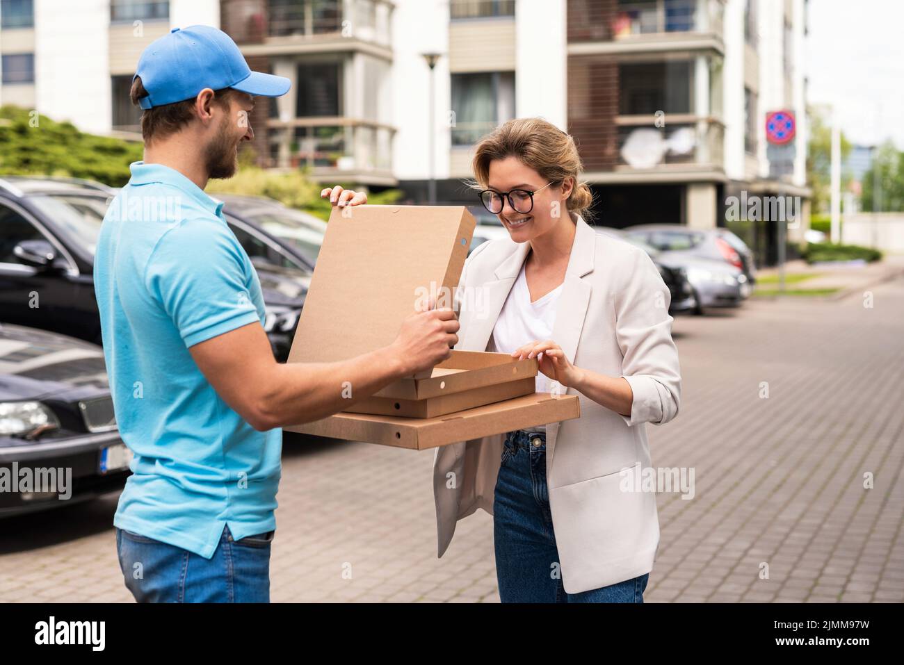 Delivery man wearing blue uniform delivers pizza to a woman client Stock Photo