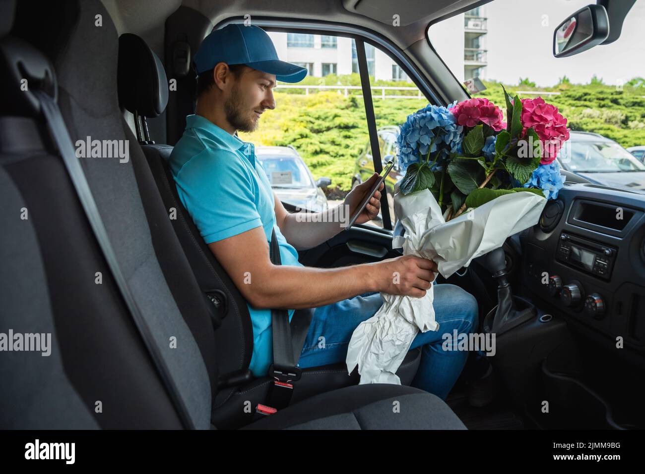 Courier inside the white van during flowers delivery Stock Photo