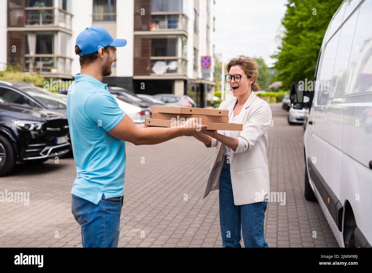Delivery man wearing blue uniform delivers pizza to a woman client Stock Photo