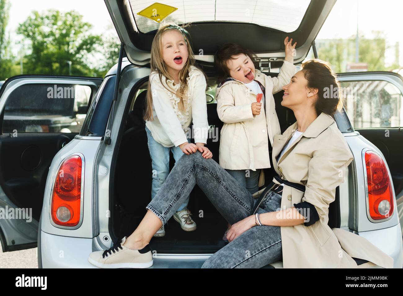 Young mother and her adorable dauthers sitting in a car trunk Stock ...
