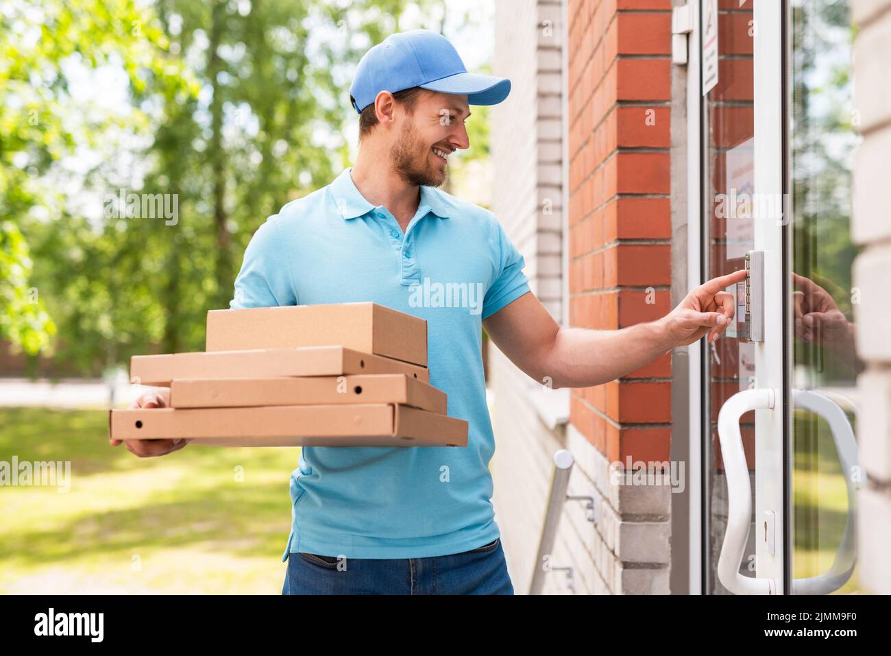 Courier during pizza delivery near an entrance of a building Stock Photo