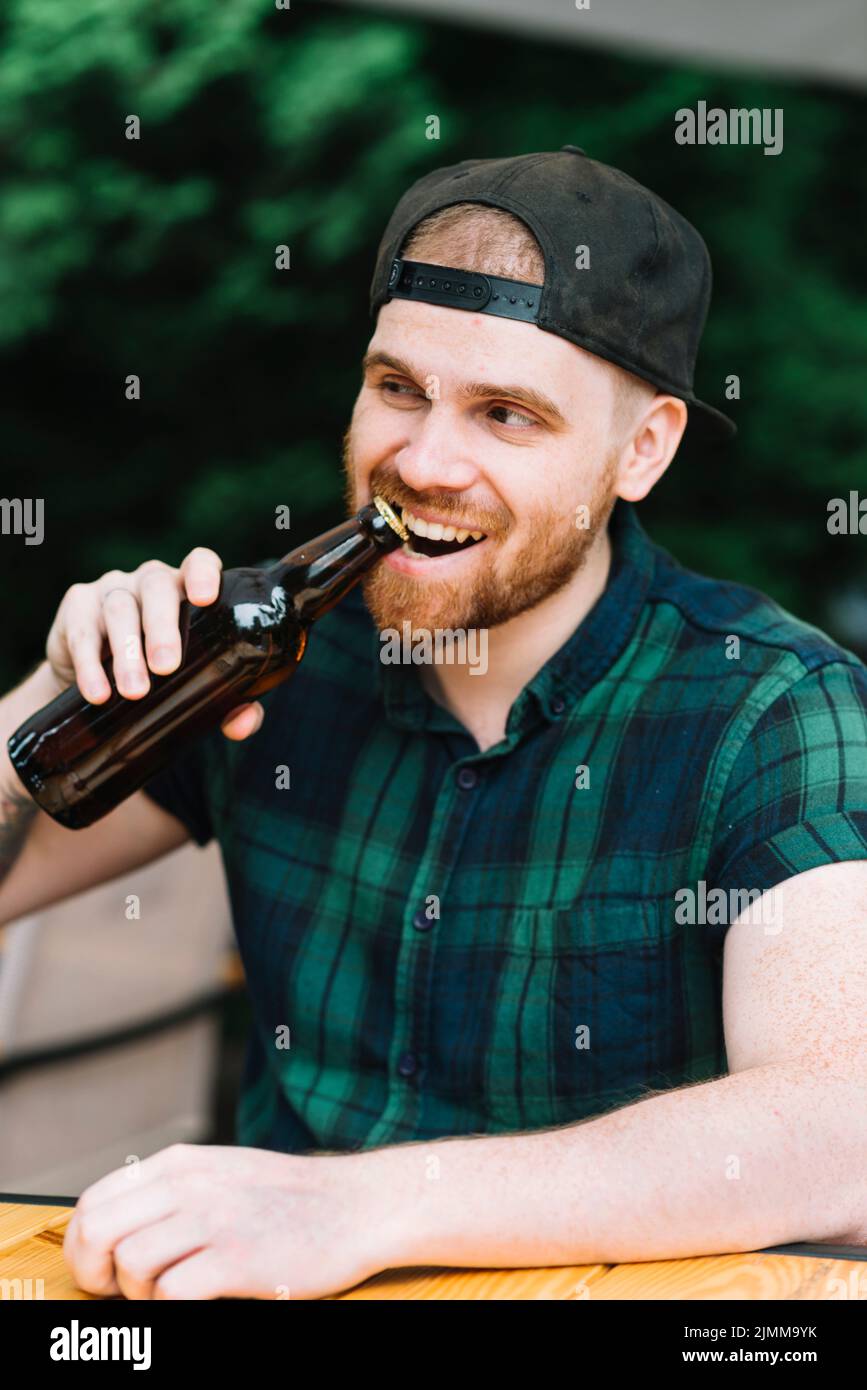 Man opening beer bottle cap with his teeth Stock Photo