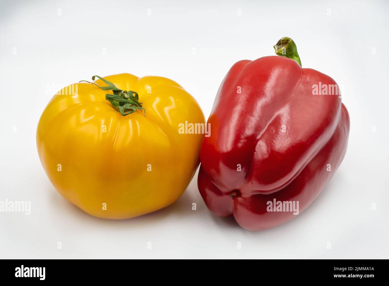 Whole yellow tomato and red bell pepper closeup against white Stock Photo